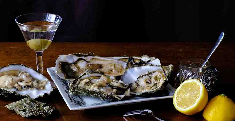 Oysters on plate with wine glass and lemon